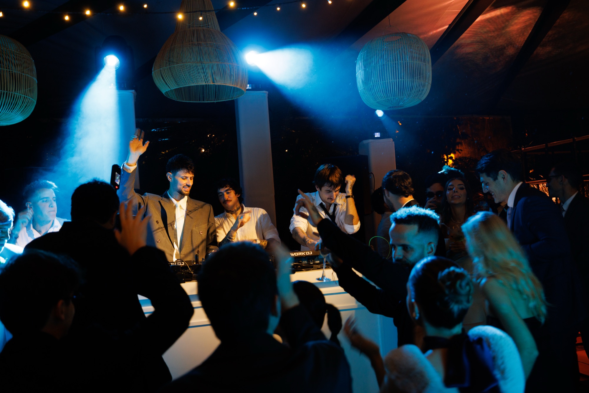 Pista cheia em frente à cabine do DJ com luzes azuis em festa de casamento